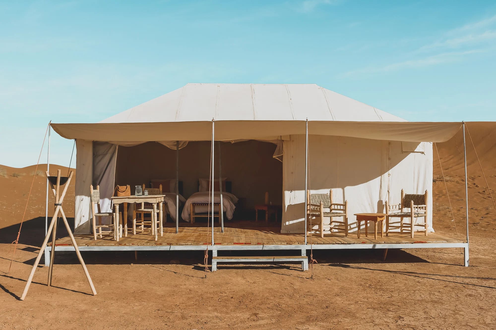 Tenda sobre plataforma de madeira, com duas camas visíveis dentro